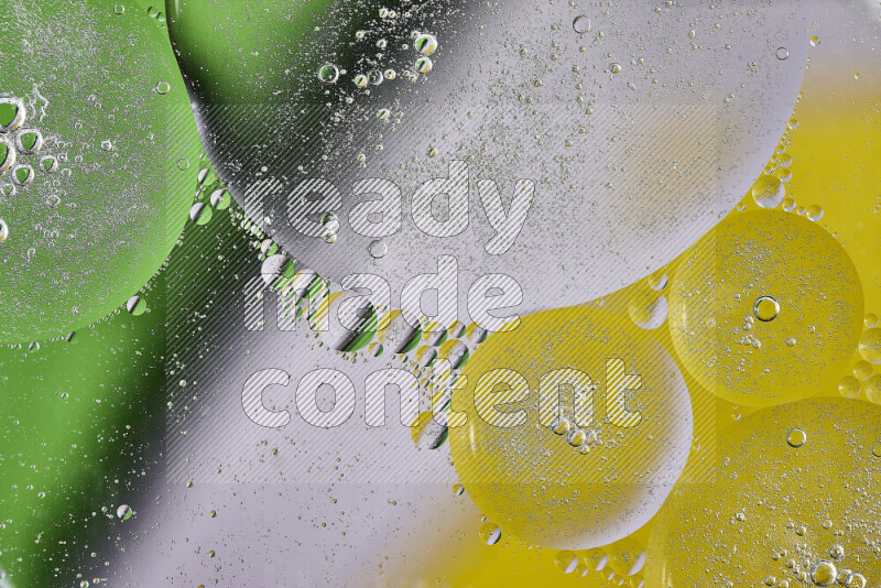 Close-ups of abstract oil bubbles on water surface in shades of yellow, green and white