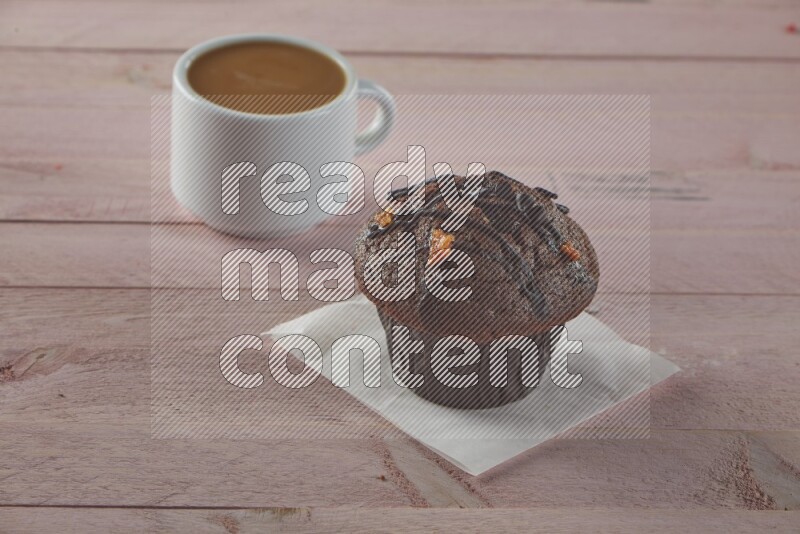 Chocolate cupcake topped with chocolate chips on a wooden pink background