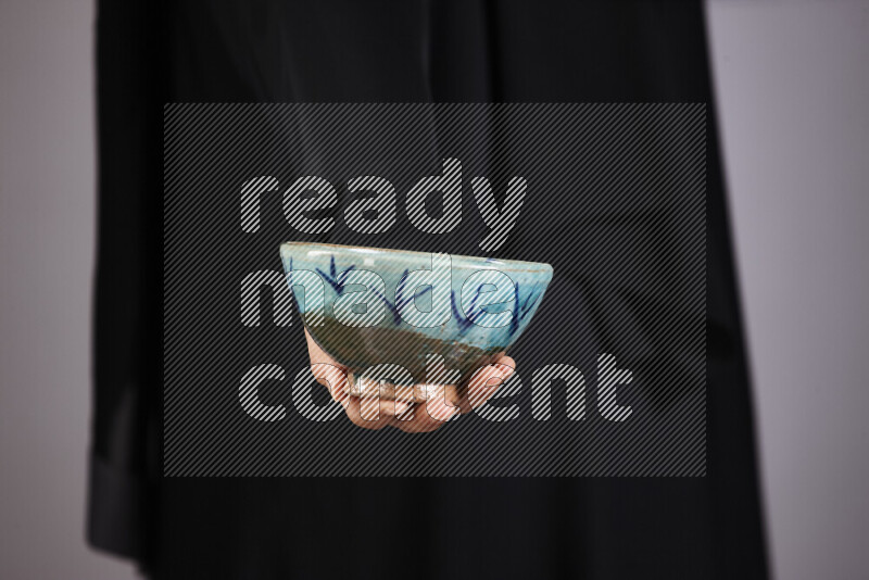 A woman in black abaya holding different pottery essentials in different positions
