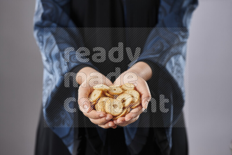Woman in abaya holding different kinds of snacks in different positions