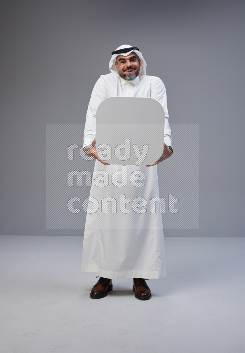 Saudi man Wearing Thob and white Shomag standing holding social media sign on Gray background