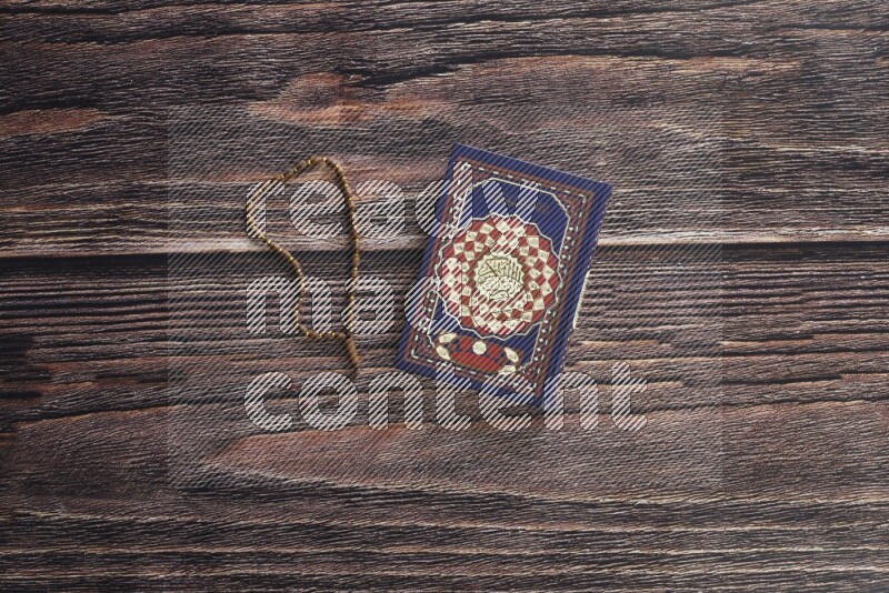 Quran with a prayer beads on wooden background