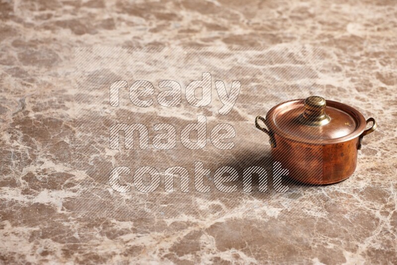 A small copper pot on beige marble background