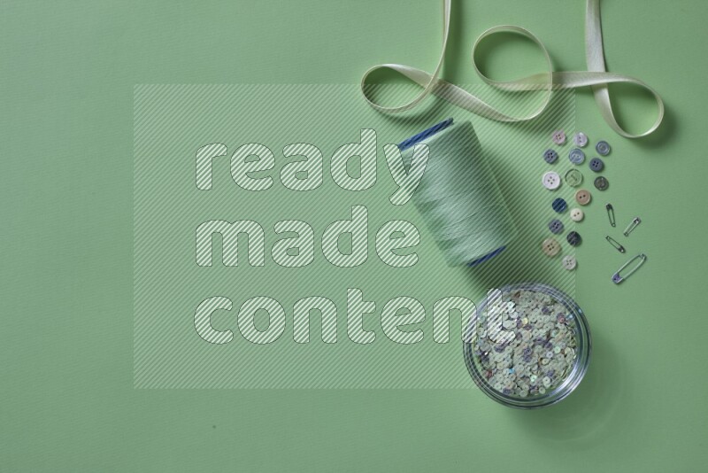 A green collection of sewing and tailoring tools arranged on a green background