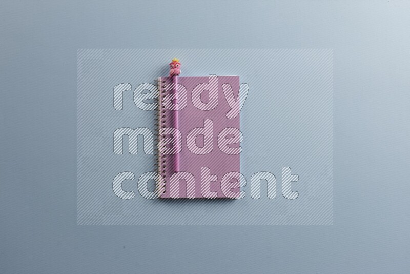 A purple notebook with different school supplies on blue background