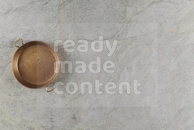 A small copper pan on grey marble background