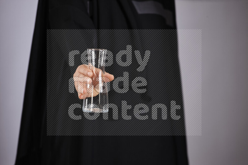 A woman in black abaya holding different glassware in different positions