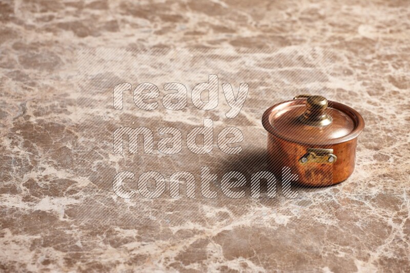 A small copper pot on beige marble background