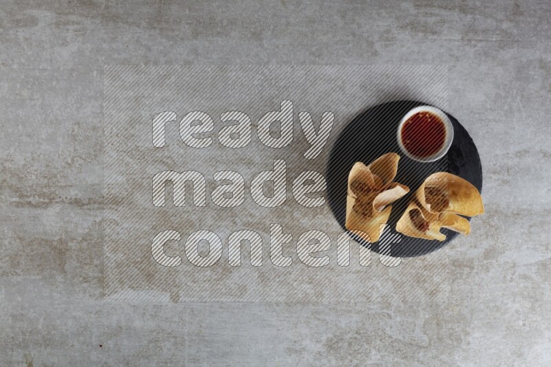 wonton cups with soy sauce ramkin on circle slate on grey textured counter top