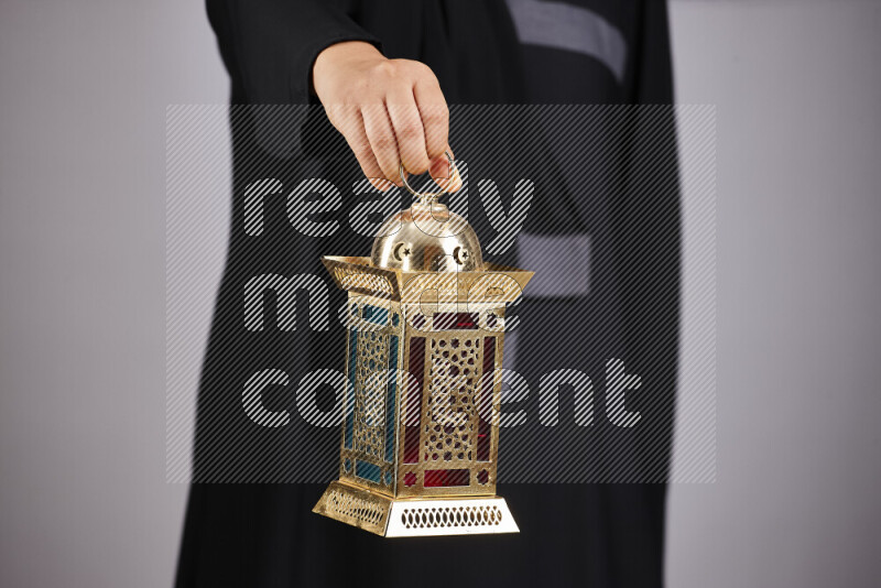 A woman in black abaya holding different ramadan lanterns in different positions
