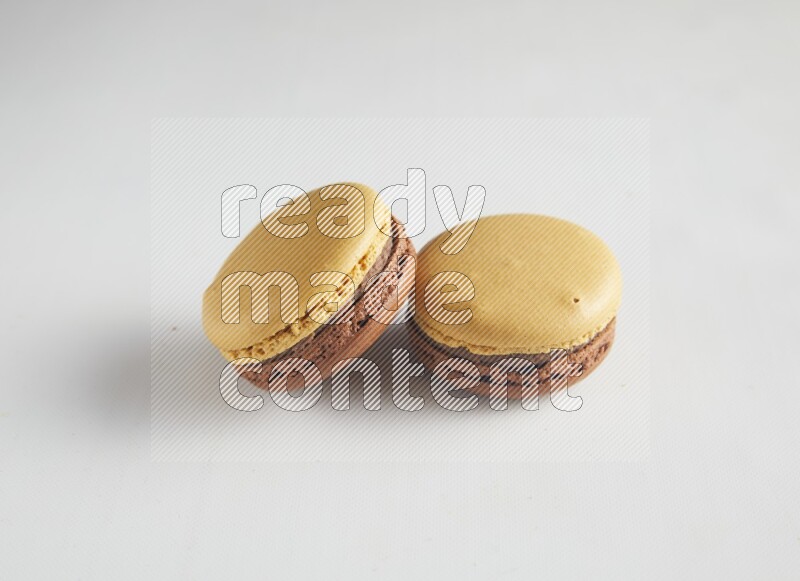 45º Shot of two Yellow and Brown Chai Latte macarons on white background