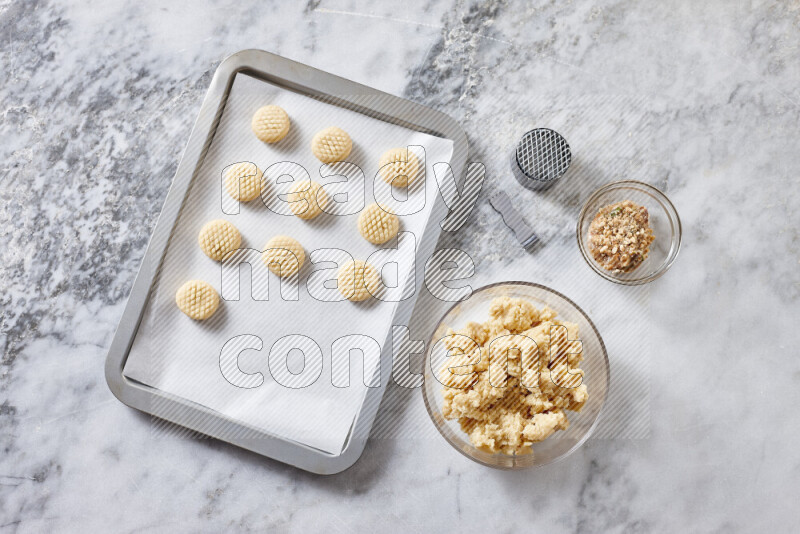 كحك خطوة بخطوة بمكوناته سمن، سكر، دقيق، سمسم، خميرة، ماء ونكهة الكحك على خلفية رخام رمادي