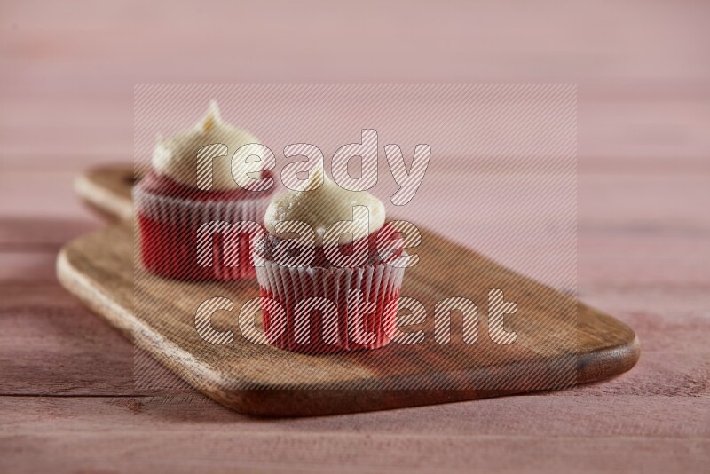 Red velvet mini cupcake topped with cream on a wooden board