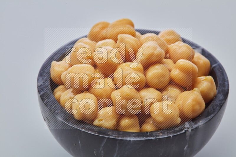 Close up shot of boiled chickpeas in a container on white background