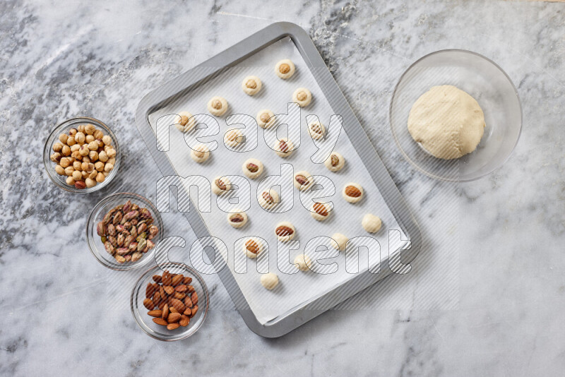 Ghoriba step by step with its ingredient, flour, powdered sugar, ghee and nuts on grey marble background
