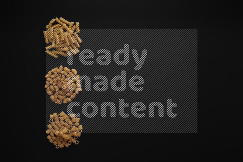 Different pasta types in 3 bunches on black background