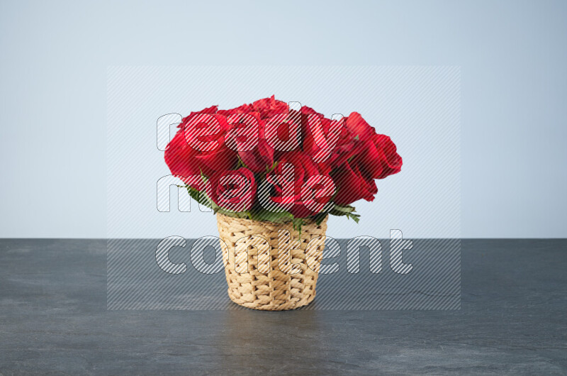 Vibrant red roses in a wicker basket on black marble background