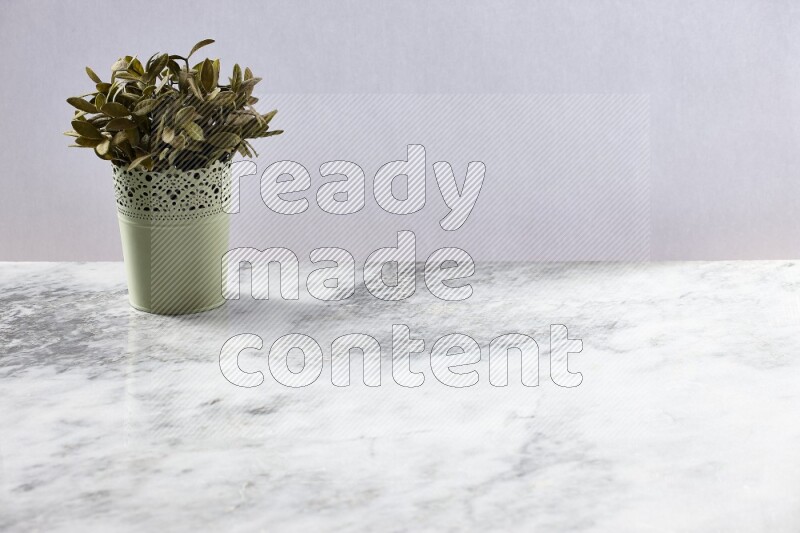 Artificial plant in green decorative pot on grey marble background