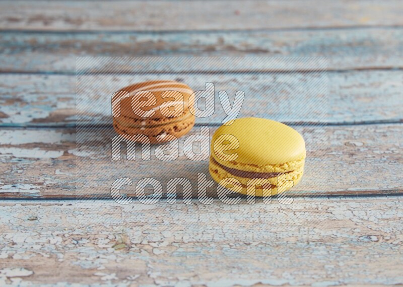 45º Shot of of two assorted Brown Irish Cream, and Yellow Lemon macarons on light blue background