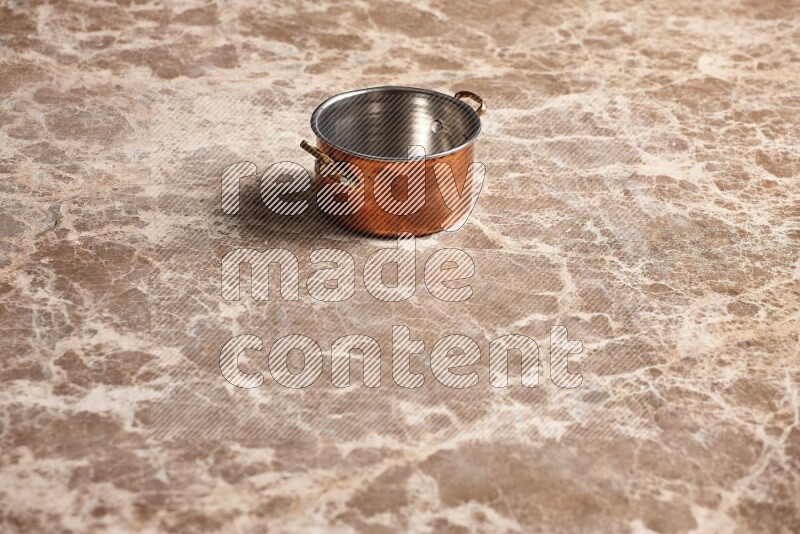 A small copper pot on beige marble background