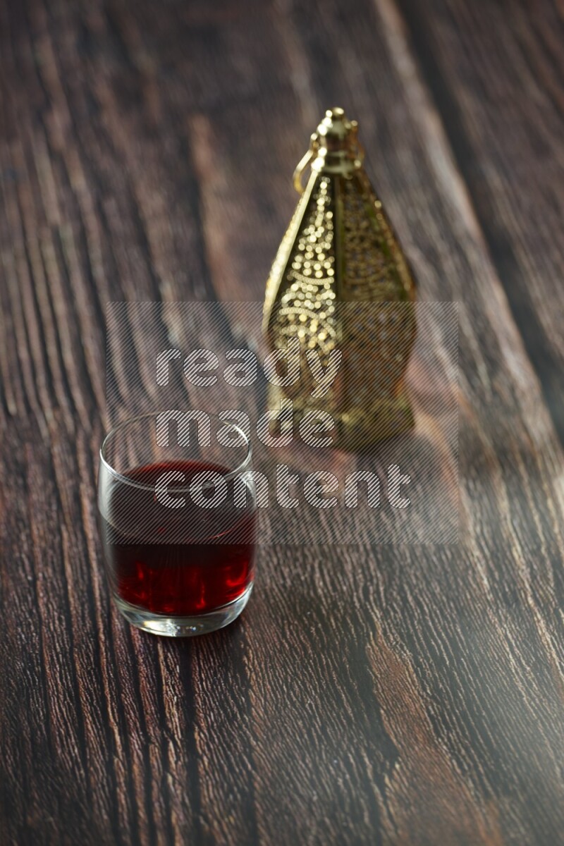A golden lantern with different drinks, dates, nuts, prayer beads and quran on brown wooden background