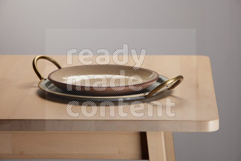 multicolored plate placed on a rounded stainless steel tray with golden handels on the edge of wooden table