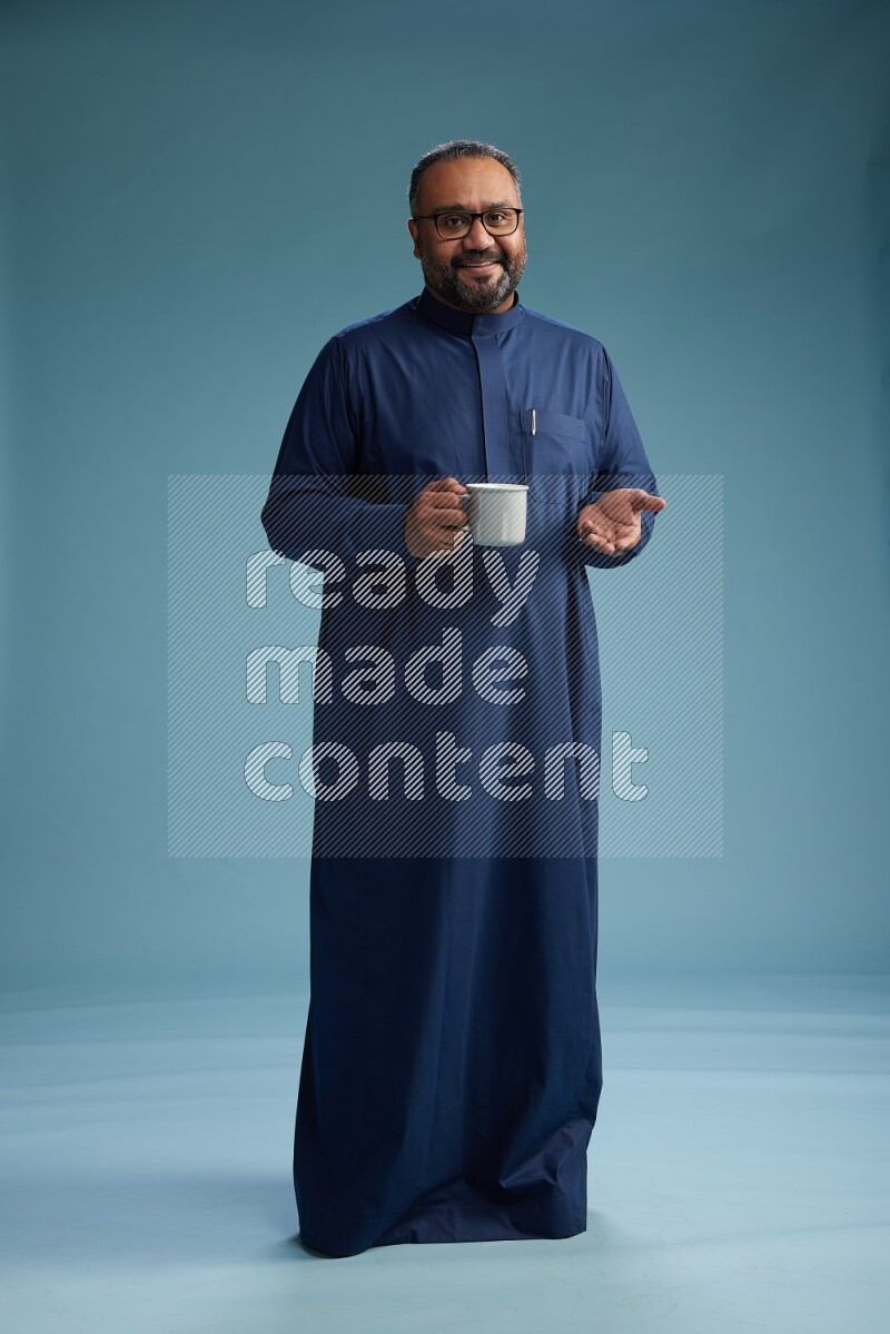Saudi Man without shimag Standing drinking coffee on blue background