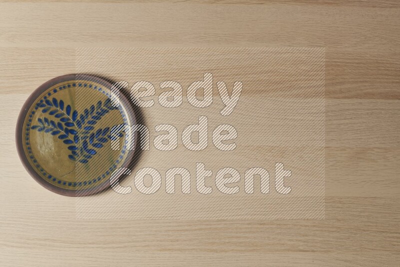 A decorative pottery plate on light wooden background