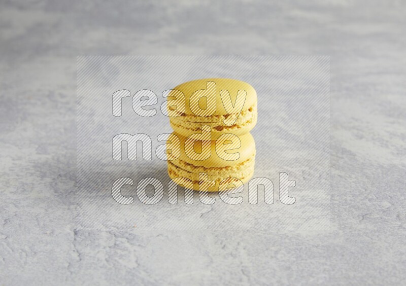 45º Shot of two Yellow Lemon macarons  on white  marble background