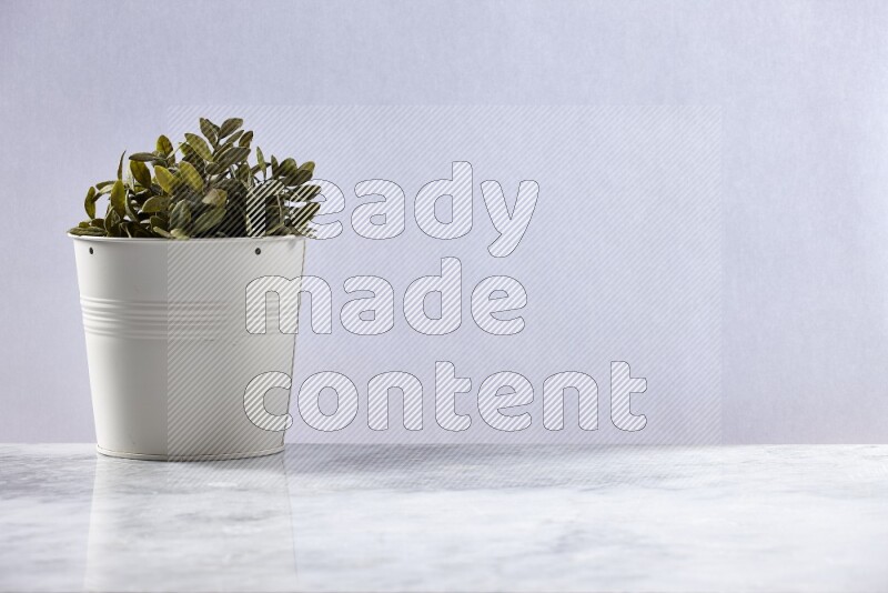 Green artificial plant in white pot on grey marble background
