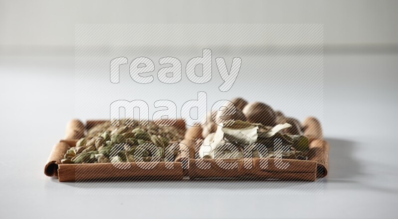 4 squares of cinnamon sticks full of nutmegs, bay laurel leaves, cardamom and cumin on white flooring