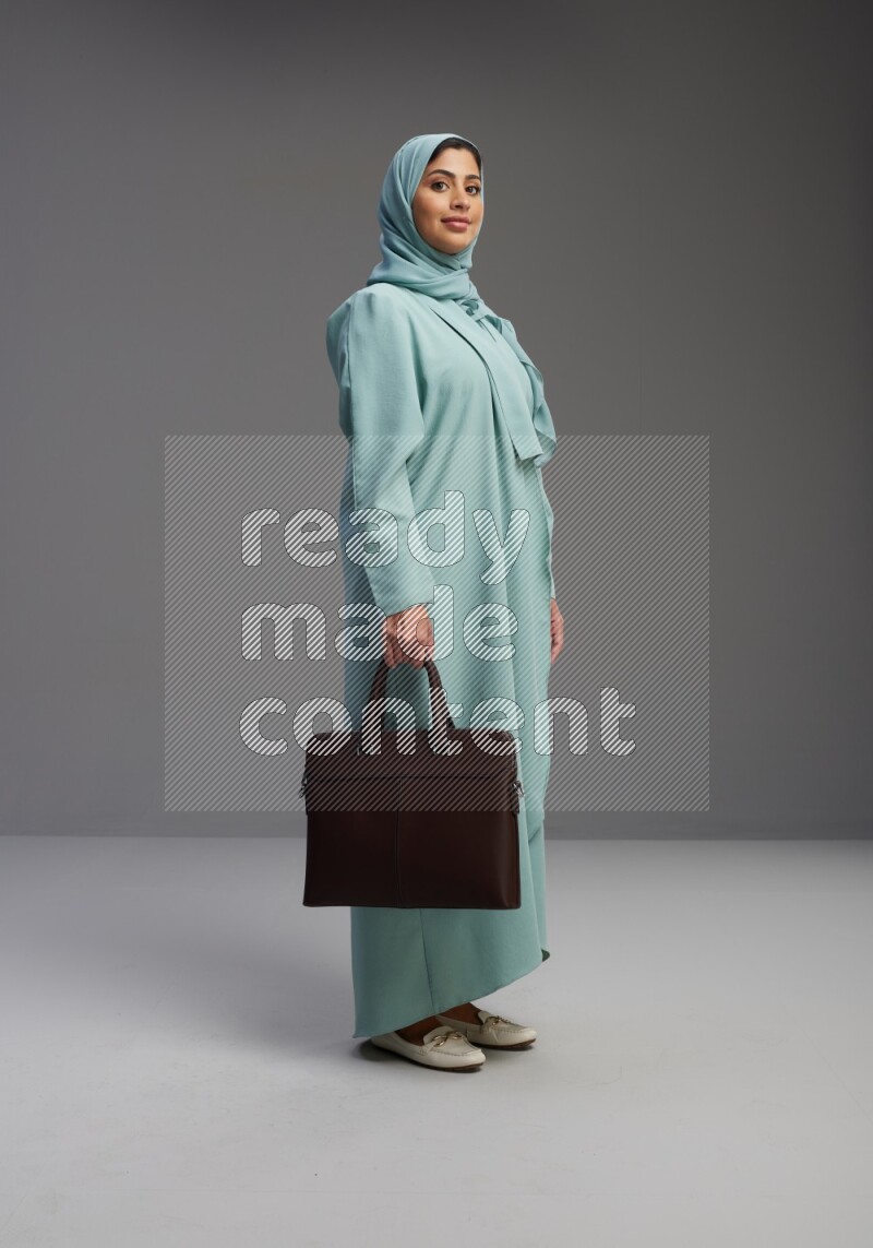 Saudi Woman wearing Abaya standing holding bag on Gray background