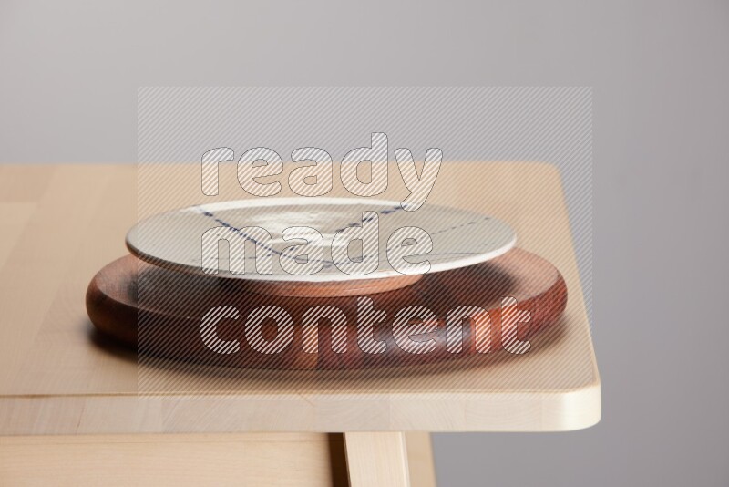 multi-colored pottery Plate placed on a dark colored wooden tray on the edge of wooden table