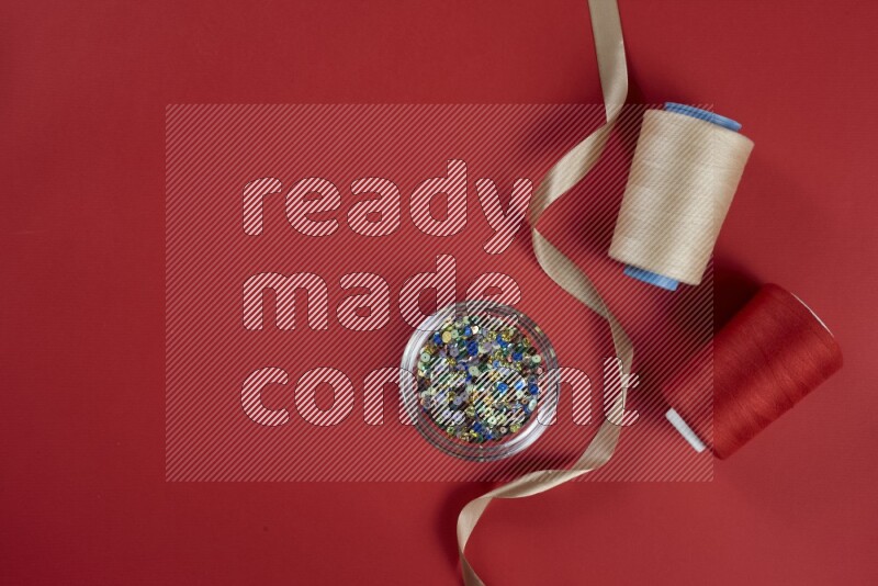 A brown and red collection of sewing and tailoring tools arranged on a red background