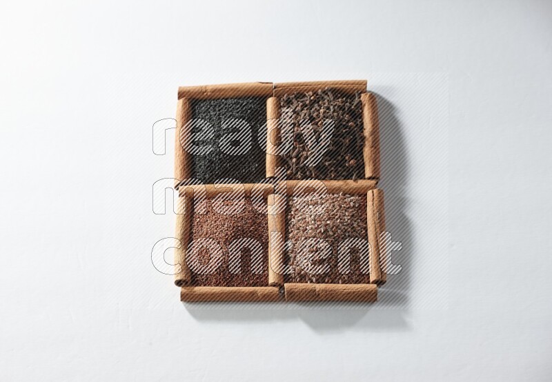 4 squares of cinnamon sticks full of black seeds, cloves, flaxseeds and garden cress on white flooring