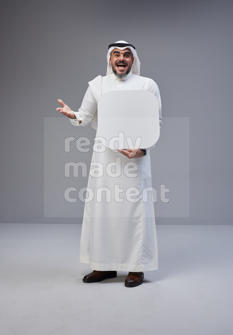 Saudi man Wearing Thob and white Shomag standing holding social media sign on Gray background