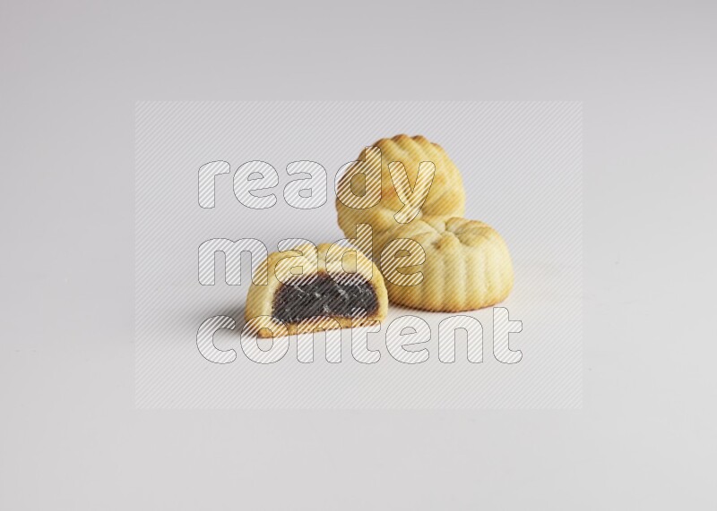 Three Pieces of Maamoul filled with date one of them is cut direct on white background