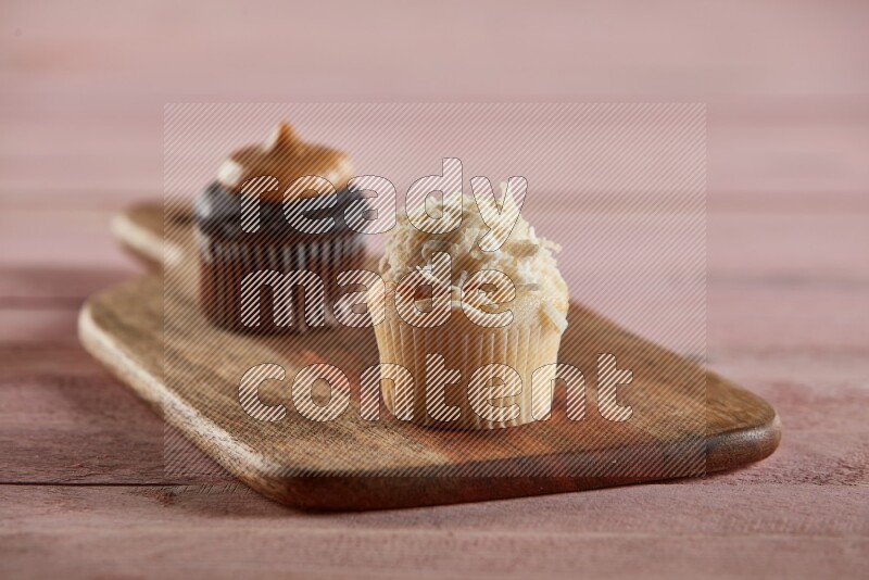 Vanilla mini cupcake topped with coconut on a wooden board