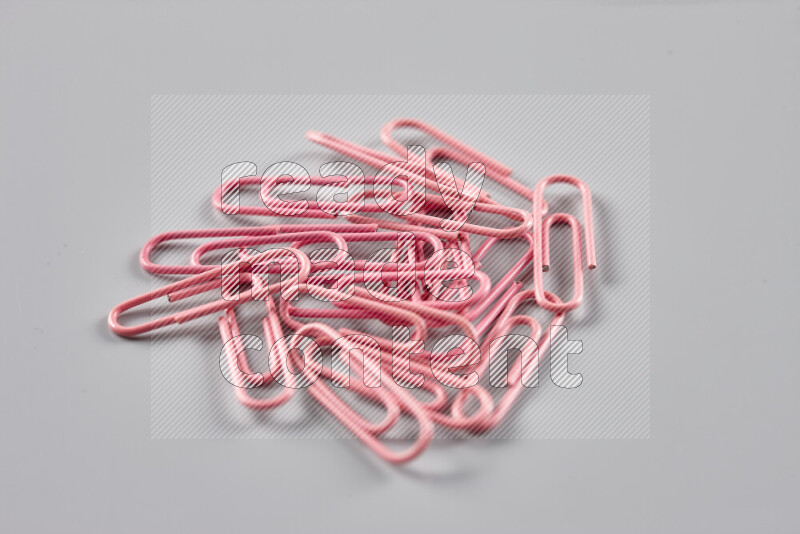 Pink paper clips isolated on a grey background