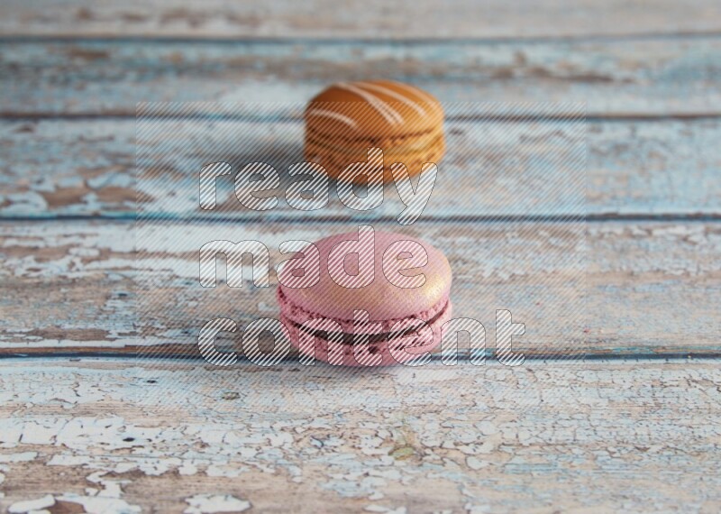 45º Shot of of two assorted Brown Irish Cream, and Purple Strawberry macarons  on light blue background