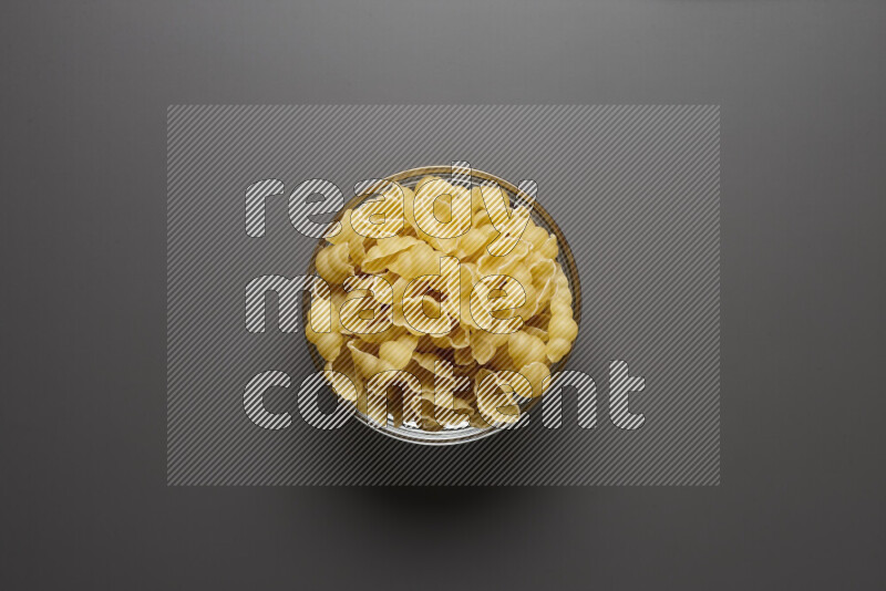 Snails pasta in a glass bowl on grey background