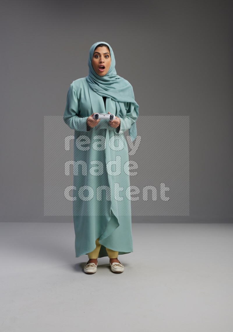 Saudi Woman wearing Abaya standing Playing Games on Gray background