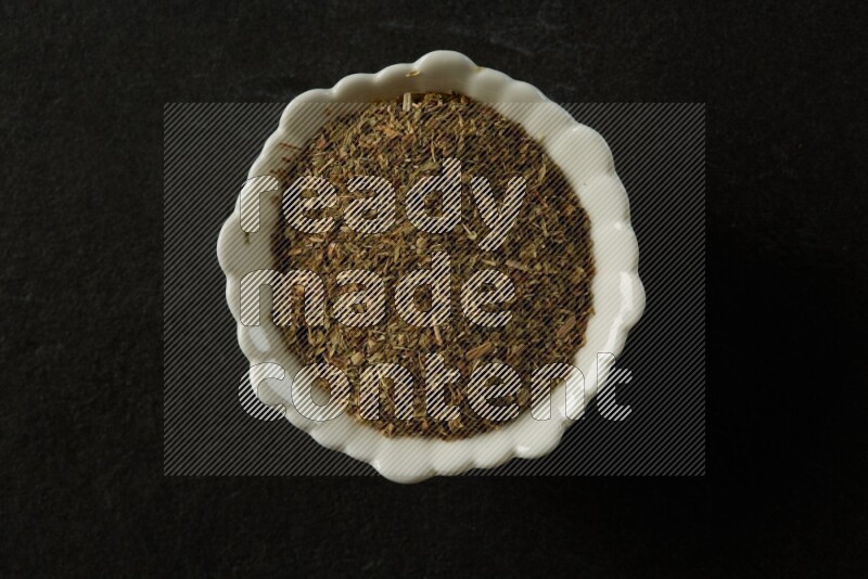white ceramic round sauce bowl filled with herbs on grey textured countertop