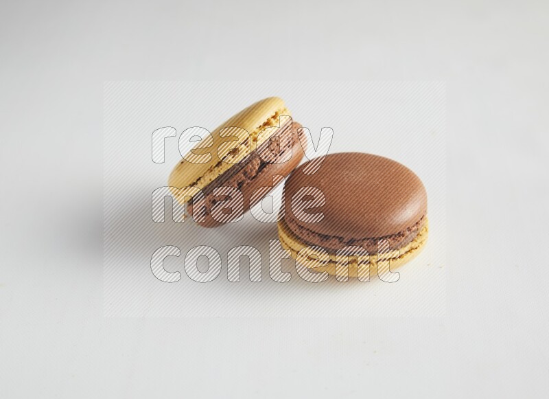 45º Shot of two Yellow and Brown Chai Latte macarons on white background