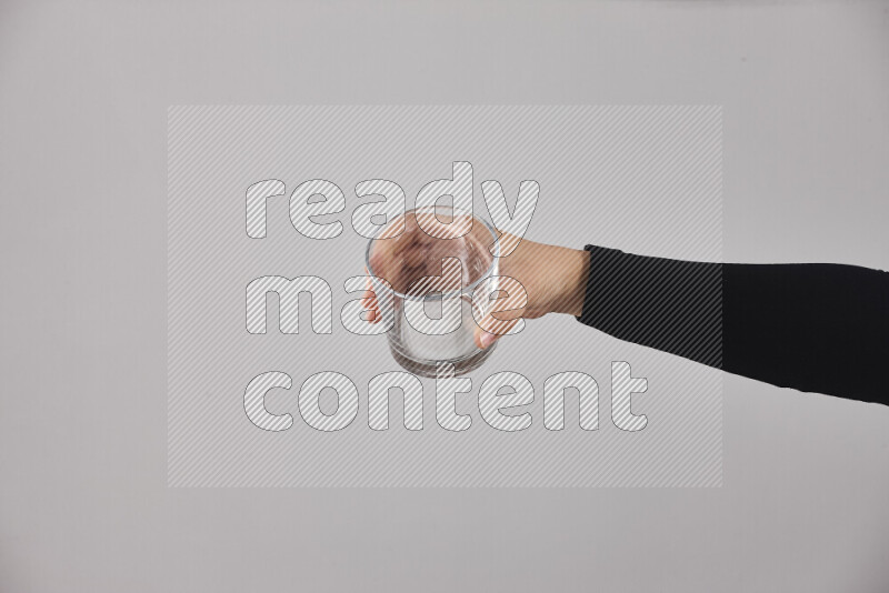 A woman in black abaya holding different glassware in different positions