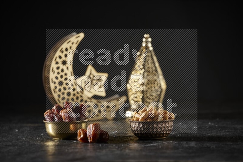 Dates in a metal bowl with cashews beside golden lanterns in a dark setup