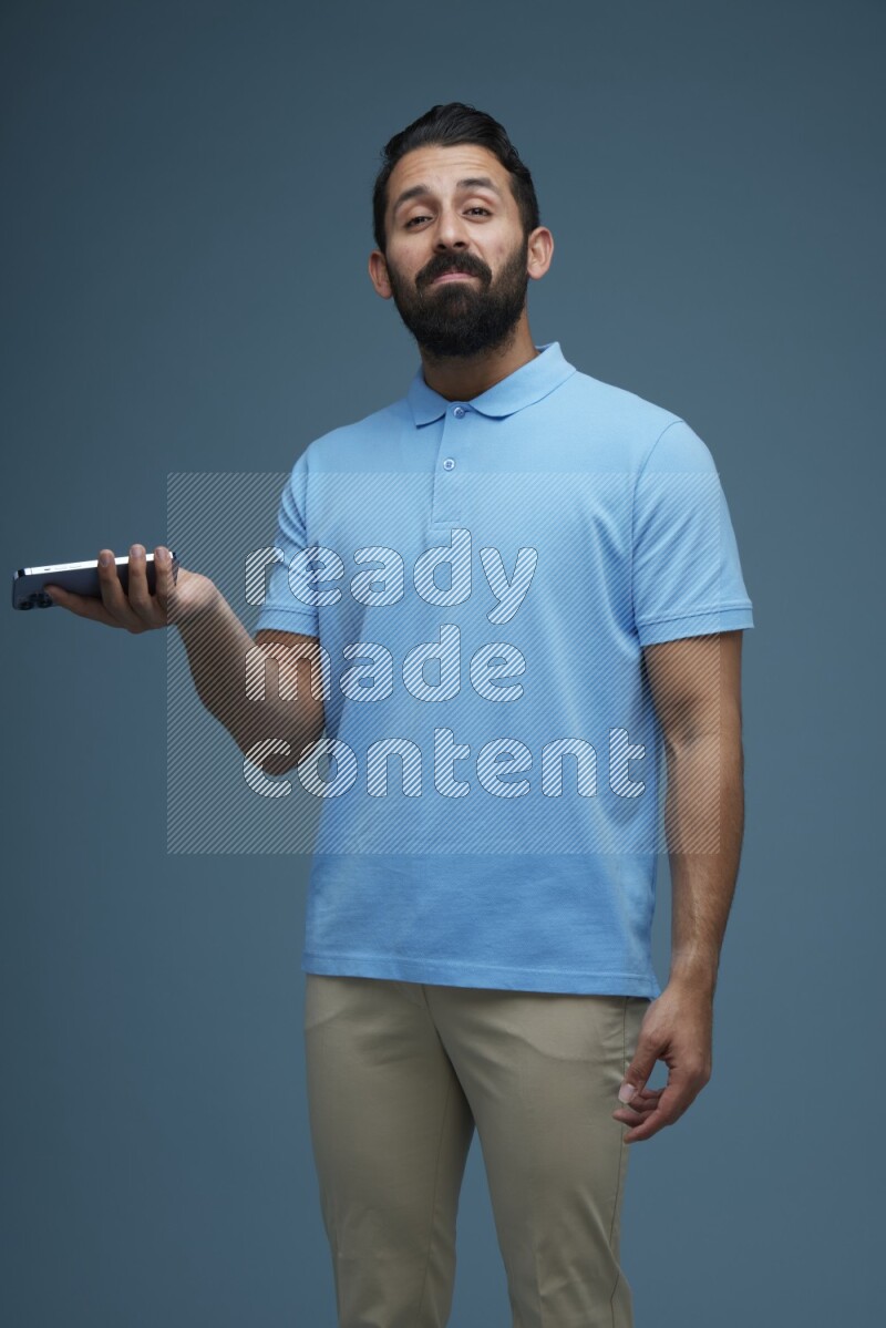 Man posing with a phone in a blue background wearing a Blue shirt