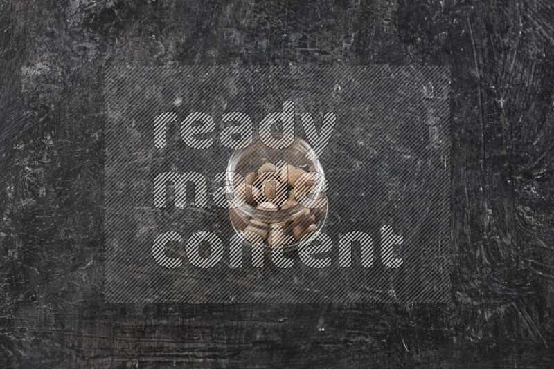 وعاء زجاجي ممتلئ بحبوب جوزة الطيب الكاملة علي خلفية سوداء