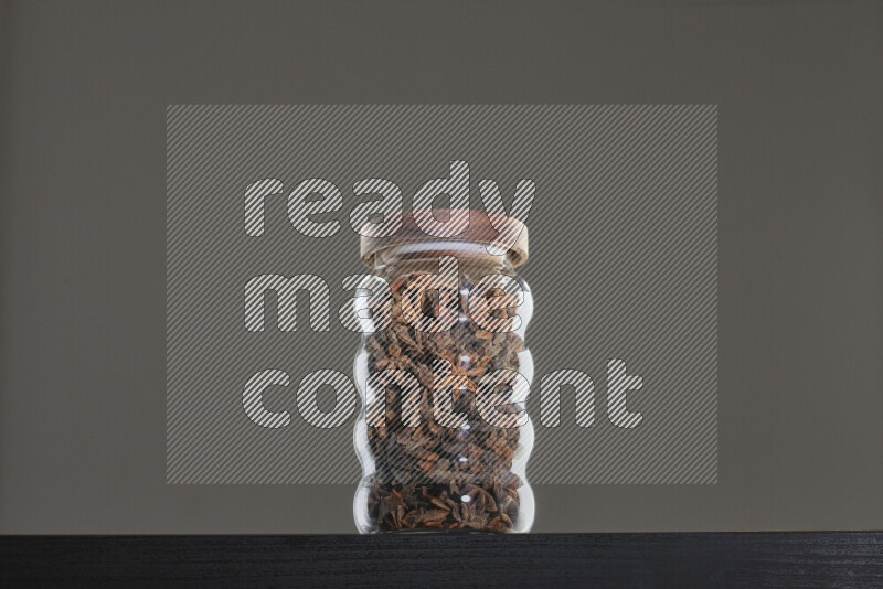 Star anise in a glass jar on black background