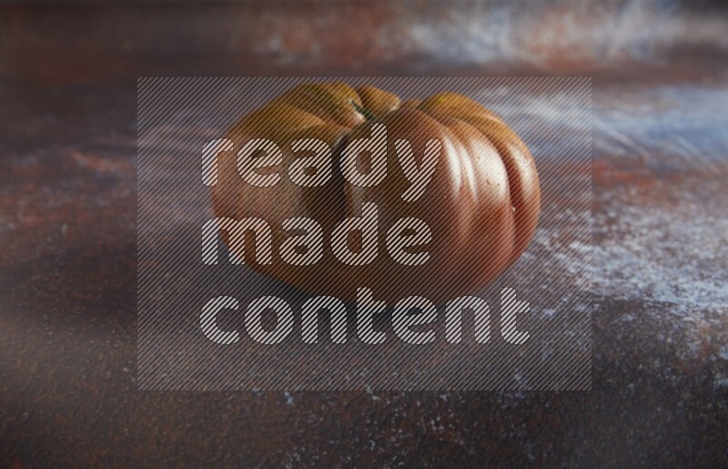 45 degree single heirloom tomato on  a textured reddish rustic metal background